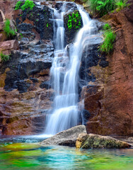 Fototapeta na wymiar Exotic cascade water flows over the rocks to the lake