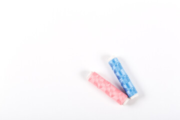 Two colored spools of pink and blue sewing thread isolated on white background. Girl or boy. Handicraft and women's hobby item with free space for text. Sewing workshop or yarn shop banner