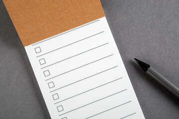 To do list. Notepad with pencil on a gray background