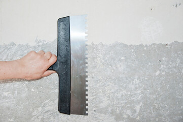 building concept. work tool and equipment. repairman working with spackling. Damaged wall repair. hand hold putty knife on gray grunge cement wall background. spatula for repair and construction