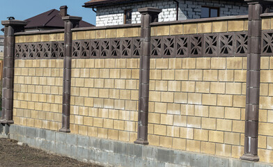 Prefabricated concrete, stone, brick new modern expensive outdoor fence to street. Wall of fence is sectional plastered with embossed road putty. Place text, concept of wealth, protection; Reliability