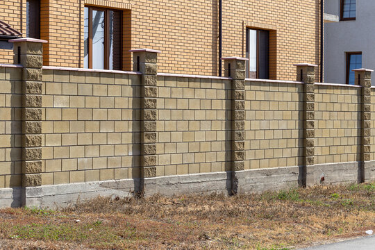Prefabricated concrete, stone, brick new modern expensive outdoor fence to street. Wall of fence is sectional plastered with embossed road putty. Place text, concept of wealth, protection; Reliability