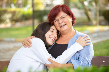 Senior mother and adult daughter embracing at the park