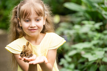 Little girl holding butterfly in her hand.