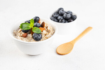 oatmeal on water with blueberries and almonds, mint, spoon on a white background, Breakfast