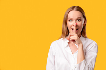 Female secret. Hush silence. Special offer. Keep quiet. Portrait of enthusiastic amazed surprised woman in white shirt showing shhh with finger at open mouth isolated on orange copy space background.