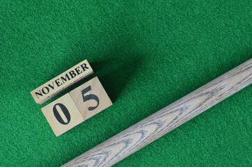 November 5, Number cube with a snooker stick on a green background, snooker table.