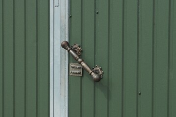 gray iron door handle and combination lock on the green metal door