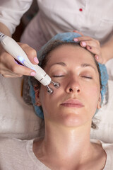 A young woman gets a beauty treatment at the hydro peeling care Spa. Beauty tools. Facial or beautician specialist