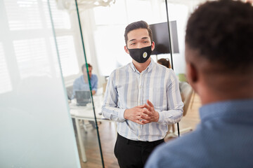 Junger Geschäftsmann mit Maske im Büro