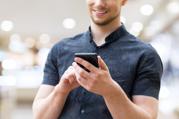 Picture of young man using a mobile smart phone and smiling.