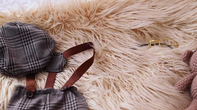 Close up shot of newborn accessories such as a teady bear, glasses and a pair of clothes.