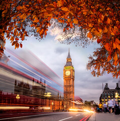 Night traffic jam with autumn leaves against Big Ben in London, England, UK