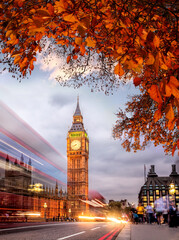 Night traffic jam with autumn leaves against Big Ben in London, England, UK