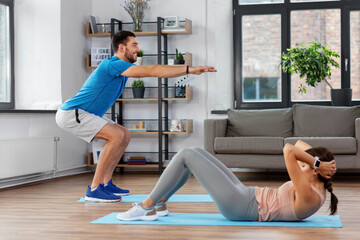 fitness, sport, training and healthy lifestyle concept - happy young man and woman exercising at home