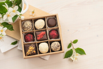 A box of chocolate mix of chocolates stands on the table in the morning light. Beautiful sweet gift for the wedding, for the birthday, for the holiday