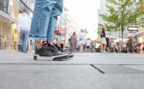 Close up photo of sneakers and blue jeans on a background of a crowded street in the center of Vienna