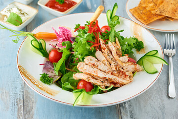 Fresh salad with grilled chicken breast, arugula and tomato. Top view