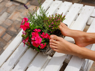 bare feet and a vase of flowers rest on a white wooden pallet.