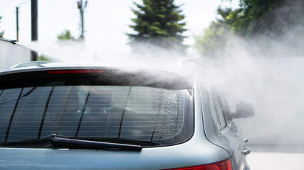 Self-service car wash. Washing a car in a carwash using a high-pressure sprayer. Gray car. Saving...