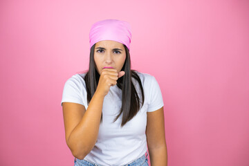 Obraz na płótnie Canvas Young beautiful woman wearing pink headscarf over isolated pink background with her hand to her mouth because she's coughing