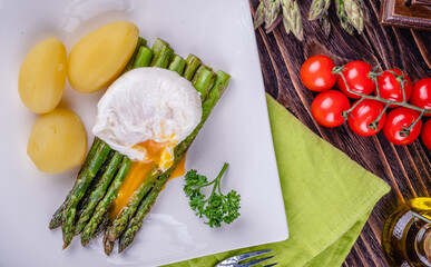 Green asparagus and boiled poached egg on a white plate.