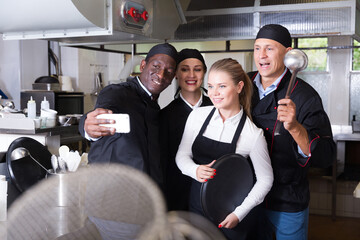Happy multinational team of restaurant staff making selfie in professional kitchen ..