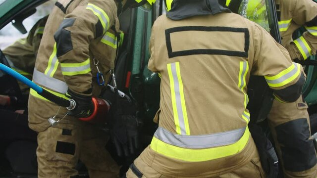 Firefighters using jaws of life to extricate trapped victim from the car. High quality 4k footage