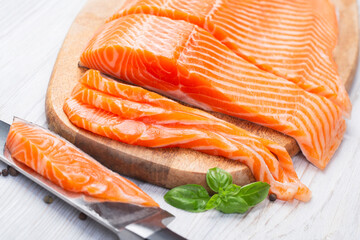 Raw fresh salmon fillet cut into slices and piece on wooden board