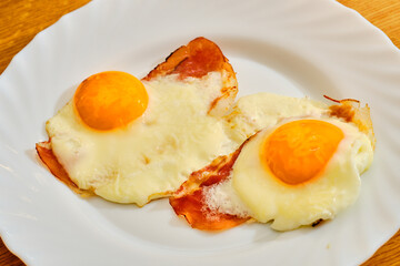 Fried eggs with bacon on white plate