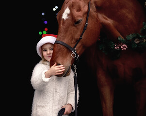 Little beautiful girl posing in christmas outfit next to a big red horse