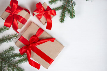 New Year's composition. Fir branches, packaging with gifts decorated with red bows on a light background. Christmas concept. Flat lay, top view. Banner.