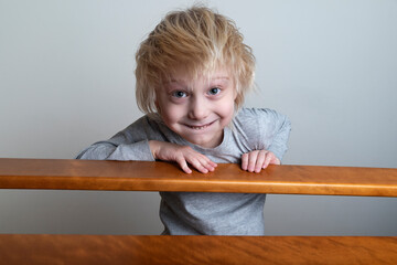 Smiling blond boy with leaned over the banister and looks down. Playing with children
