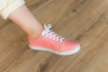 Casual pink shoes sneakers on woman feet on wooden floor background