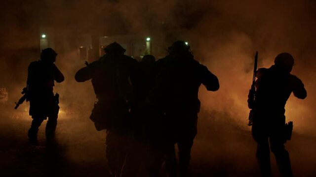 Soldiers carry a wounded soldier through a war zone