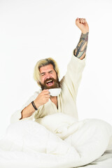 Obraz premium Man with beard in dressing gown. Guy in bath clothes hold coffee. Morning rituals concept. Tired man drinking coffee. Every morning begins with coffee. Bachelor in bathrobe