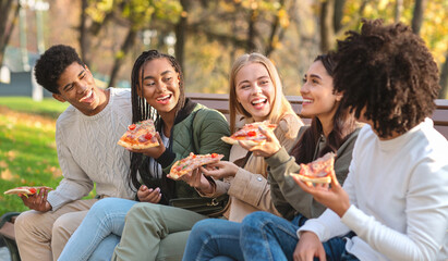 Cheerful students having break at park, eating pizza
