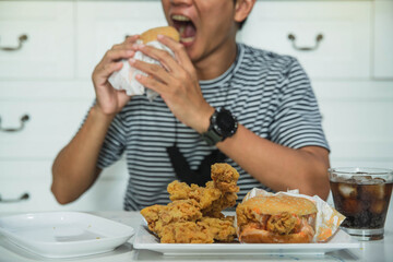 Man is eating in a restaurant and enjoying delicious food. Man  eats a delicious burger sitting in a fast food restaurant. Lunch break with bad food.