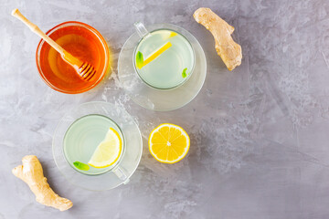 Ginger tea with lemon on a gray background. Two cups of ginger tea and ingredients for its preparation. Copy space. Top view