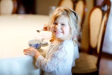 Little toddler girl eating homemade yogurt for breakfast. Cute healthy happy child having meal.