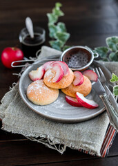 Curd buns with apple slices and powdered sugar on a gray plate. Mini cheesecakes baked in the oven. Vintage cutlery.