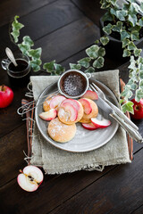 Curd buns with apple slices and powdered sugar on a gray plate. Mini cheesecakes baked in the oven. Vintage cutlery.