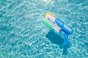 A child's blue water gun floats in the pool. A toy for playing in the pool or on the beach