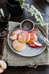 Curd buns with apple slices and powdered sugar on a gray plate. Mini cheesecakes baked in the oven. Vintage cutlery.