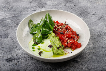 Exquisite fish tartare raw tuna fillet with greens close up on a white plate