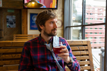 A man with a beard drinks beer in a bar or pub. Loneliness, alcohol and lifestyle concept. dependence, crisis, unemployment.