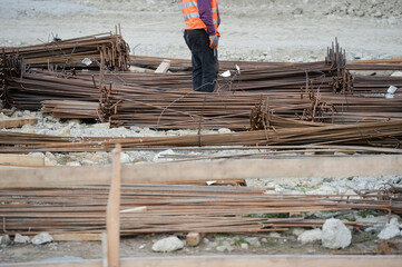 Detail with unrecognizable construction worker wearing protection equipment manipulating reinfocing iron bars on a construction site