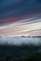Fototapeta premium Abend Nebel über Landschaft mit bewaldetem Tal