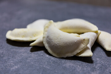 Polish gluten-free dumplings (Pierogi), polish national dish made of dough and savoury or sweet filling. Close-up view of several frozen dumplings lying on a table.