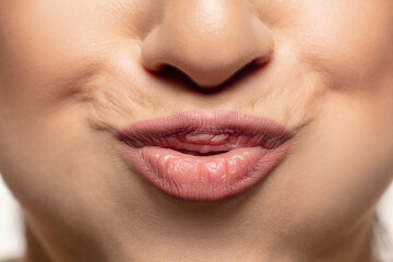 Naklejka premium Calm, cute. Close-up shoot of beautiful female lips with natural lipstick make up. Beauty, fashion, skincare, cosmetics, ad concept. Copyspace. Well-kept skin and natural fresh look. Healthy shiny.
